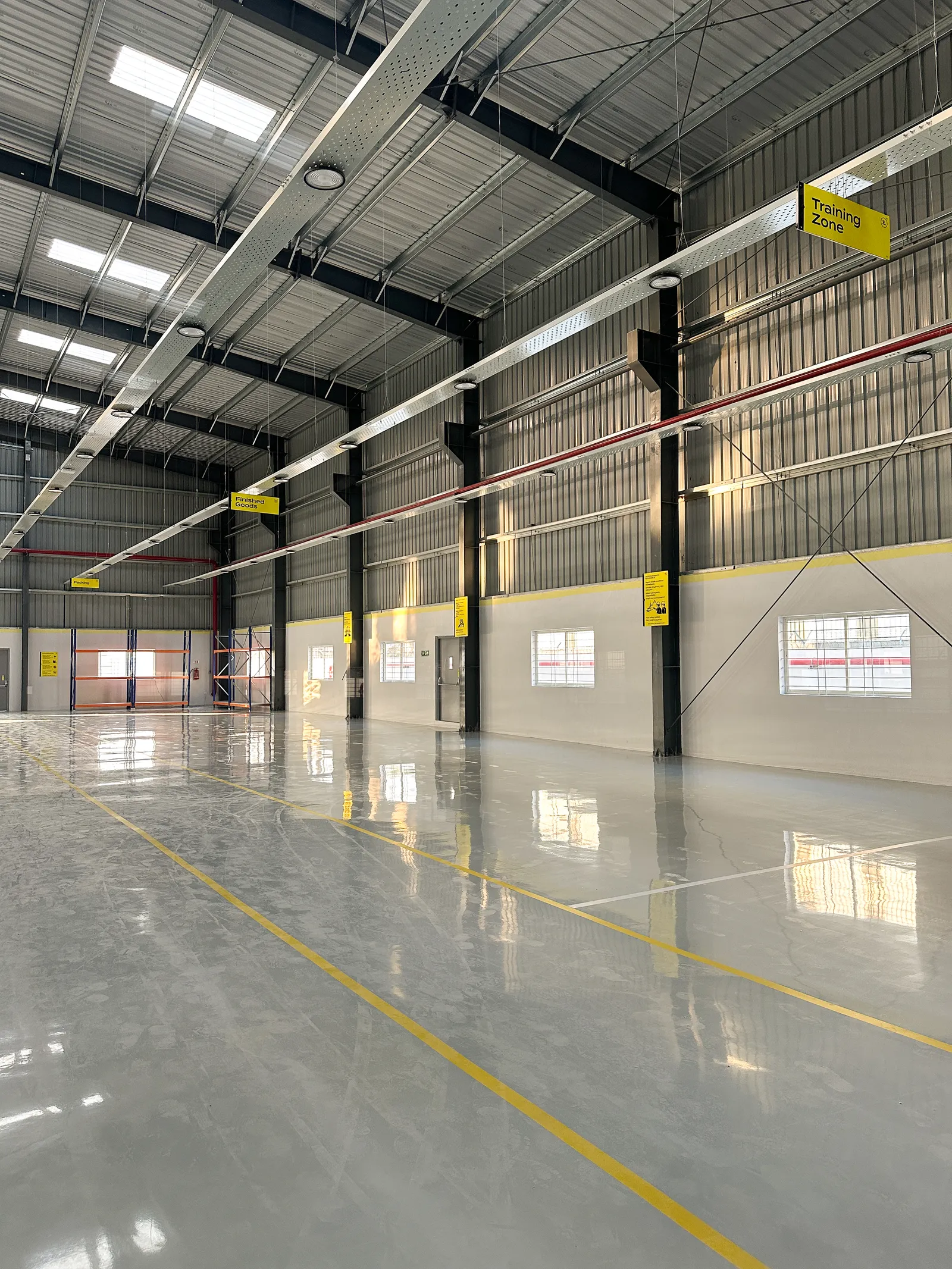 Factory interior with roof purlins and yellow floor markings — Everta